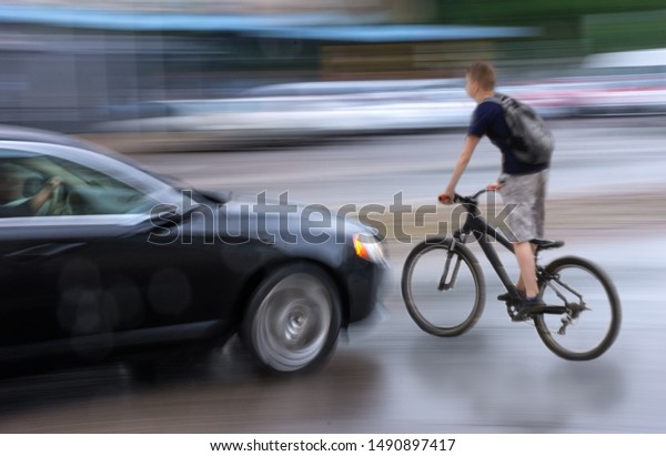 Dangerous city traffic situation\
with cyclist and car in the city in motion blur. Defocused\
image