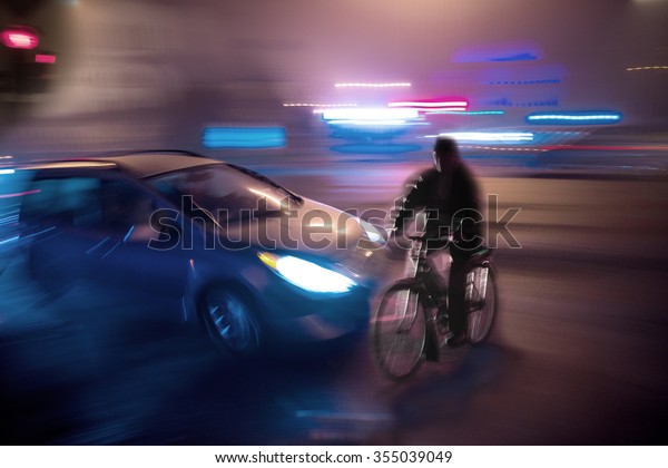 Dangerous city traffic situation with cyclist\
and car in the city at night in motion\
blur