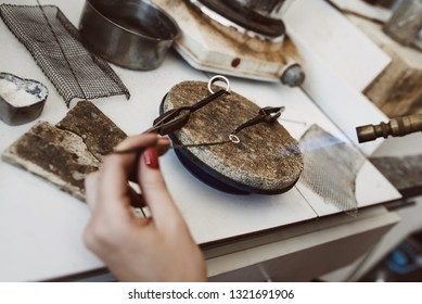 Dangerous job. Top view of jeweler's hands soldering a silver earring with flame from welding torch - Powered by Shutterstock