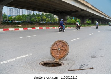 Dangerous opened manhole hole cover, opened sewerage hatch with traffic on background