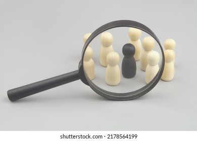 Dangerous people recognition concept. Magnifying glass and wooden people figures, one figure is black colored. - Shutterstock ID 2178564199