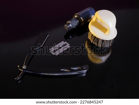 a dangerous razor, a blade, beard oil on a black background. space for text. barber kit