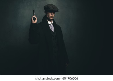 Dangerous retro 1920s english gangster standing with gun.