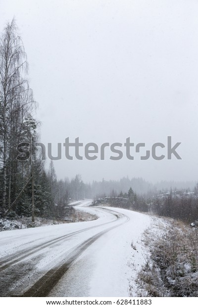Dangerous road to drive. A curvy\
road during snow blizzard. Heavy snow storm hit during a spring\
day.