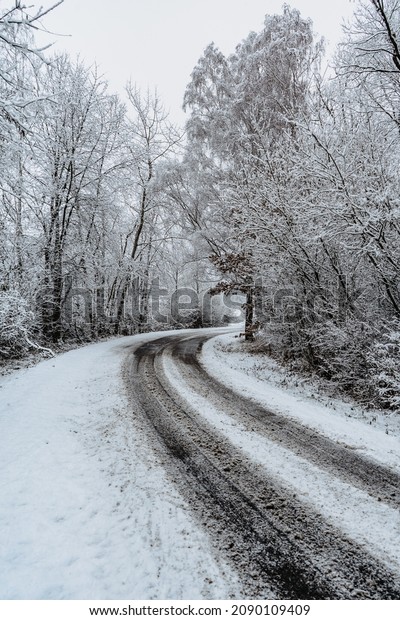 Dangerous stretch of road covered with snow and\
ice.Snowy road through forest.Winter panorama.Driving in icy frozen\
landscape.Bad weather conditions.Slippery asphalt road.Weather\
forecast scene