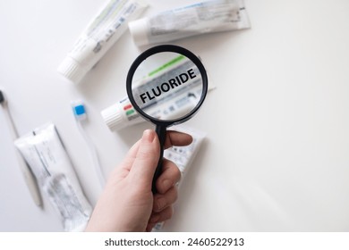 Dangerous toothpaste ingredient fluoride. Checking the composition of toothpaste with a magnifying glass against the background of many tubes