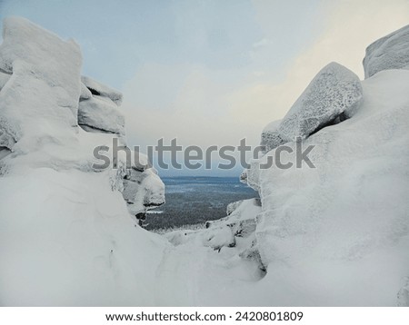 Dangerous winter gorge, a cliff between two snow rocks. Dramatic view among giants rocky mountains.  Low clouds and beautiful rockies. 