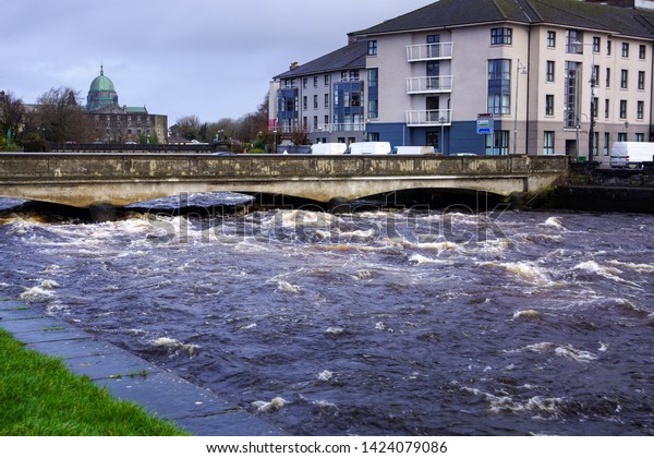 Dangerously strong current\
on river that about to flood or go over bridge and riverbanks in\
Galway, Ireland