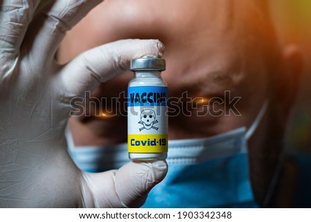 The dangers of coronavirus vaccination. Harmful side effects concept. A devilish doctor holds a vial of vaccine with a toxicity warning sign.
