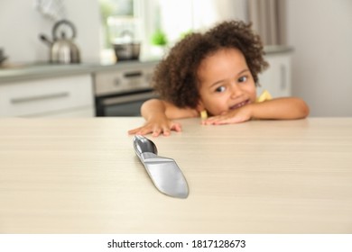 Dangers In Kitchen. African American Girl Reaching After Knife At Table