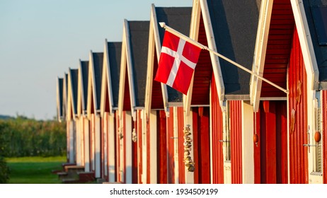 The Danish flag Dannebrog and red fishing huts on the baltic sea coast