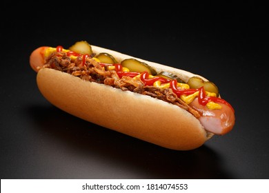 Danish hot dog with pickled cucumbers, fried onions and a hot dog with mustard, lettuce and jalapenos on a black background. - Powered by Shutterstock