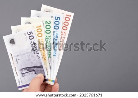 Danish money - crowns -  in the hand on a gray background