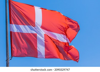 Danish National Flag Waving On Blue Sky Background. Kingdom Of Denmark, DK