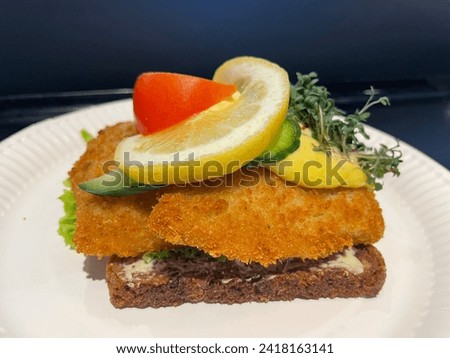 Danish national sandwich with black bread, fried fish in batter and a slice of lemon