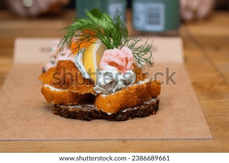 Danish open sandwich made of rye bread, fried fish and shrimp on a table in a cafe, fast food.