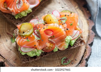 Sandwich danois ouvert Smorrebrod avec du saumon sur du pain de seigle avec des légumes et des herbes