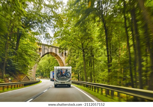 Dannenberg, Germany - September 20, 2021:\
Camper with a bike carrier and bicycles mounted on it on a country\
road. The focus lies on the camper, the rest of the photo is\
blurred by\
movement.