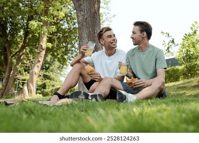 A dapper couple enjoys refreshing drinks and smiles while sitting on the grass. - Powered by Shutterstock