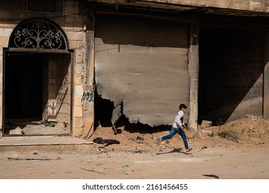 Darayya, Syria - April, 2022: Young Boy Running On Street In Destroyed City After The Syrian Civil War.