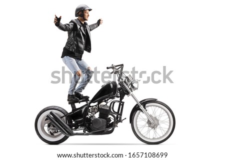 Daredevil riding a customized motorbike and standing on the seat isolated on white background