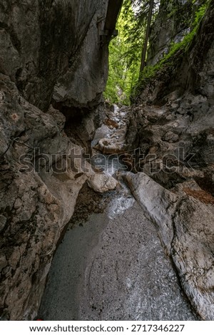 A daring descent along rugged cliffs reveals a serene, sunlit gorge with cascading water, evoking thrill and tranquility in Slovenias breathtaking Triglav National Park