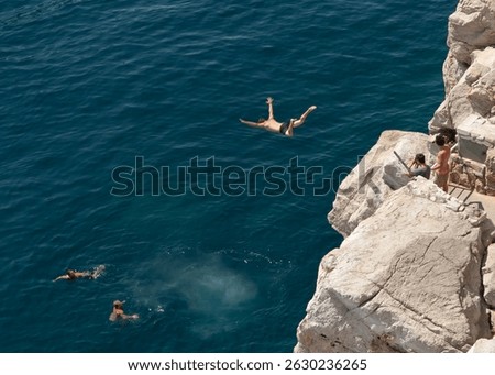 A daring diver leaps off the cliffs of old Dubrovnik into the Adriatic Sea.  Friends await below.