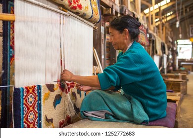 Darjeeling, India - April 19, 2017: Unidentified tibetan woman works as weaver in the carpet workshop of Tibetan Refugee Self Help Center, Darjeeling, India