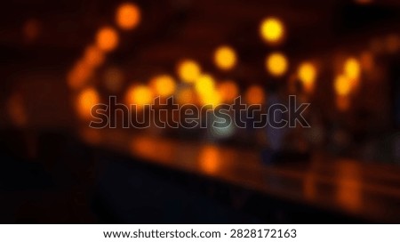 A dark, abstract background filled with blurred warm orange and yellow bokeh lights, creating a festive and atmospheric mood.