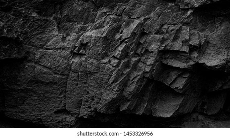 Dark Aged Shabby Cliff Face And Divided By Huge Cracks And Layers. Coarse, Rough Gray Stone Or Rock Texture Of Mountains, Background And Copy Space For Text On Theme Geology And Mountaineering.
