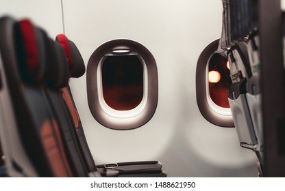 A Dark Aircraft Interior: The Row Of Modern Empty Leather Seats With Armrests Down, Shallow Depth Of Field, Selective Focus On The The Window With A Night Lights Outside