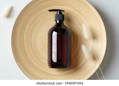 Dark amber glass bottle and dried flowers on plate. Natural skincare SPA beauty product design. Flat lay, top view.