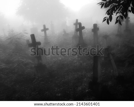 Dark ancient cemetery in the fog. Crosses and graves in a spooky abandoned cemetery. Place of burial. 