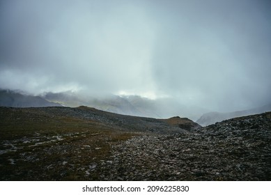Dark atmospheric landscape on edge of abyss in highlands. Dangerous mountains and abyss among low clouds. Danger mountain pass and sharp rocks in clouds. Dangerous cloudy rainy weather in mountains.