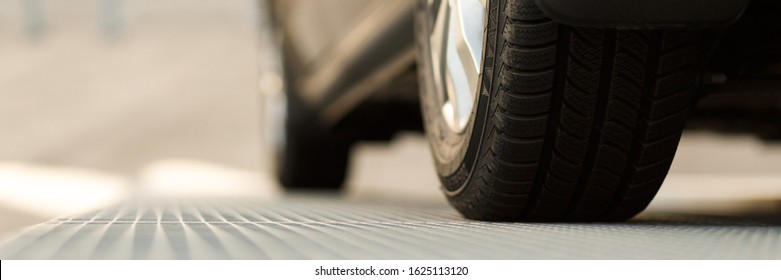 Dark Automobile Standing On Steel Floor View From Below. Car Parking Problems, Motor Show Or Exhibition, Winter Season Tires, Customer Purpose Loan, Vehicles Official Checkup Or Examination Concept