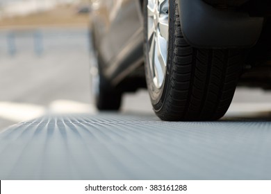 Dark Automobile Standing On Steel Floor View From Below. Car Parking Problems, Motor Show Or Exhibition, Winter Season Tires, Customer Purpose Loan, Vehicles Official Checkup Or Examination Concept