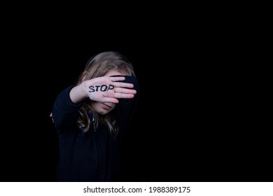 dark background. a girl in a dark dress closes her eyes. The palm is extended forward. Stop sign.