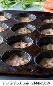 A Dark Baking Muffin Tin Filled With Carrot Cake Muffin Batter.