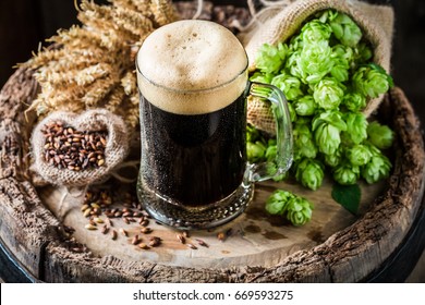 Dark Beer With Foam, Wheat And Hops On Oak Barrel