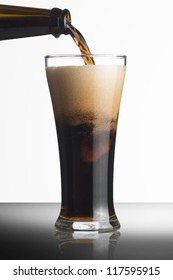 Dark Beer Pour From Bottle To Glass On White Background