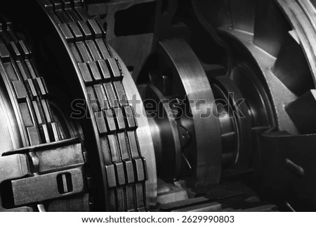 A dark black close up of a machine with many gears and discs. concept of powerful industrial energy of complexity and intricacy, and a sense of awe at engineering behind machine.