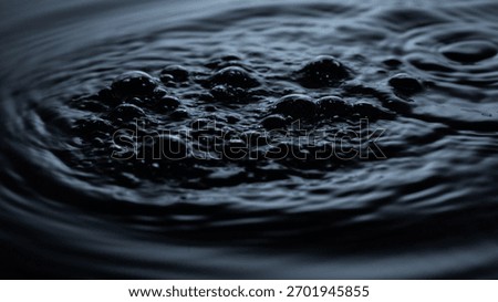 Dark black liquid with bubbles on the surface, resembling crude oil. Abstract texture of waves and light reflections on black water.