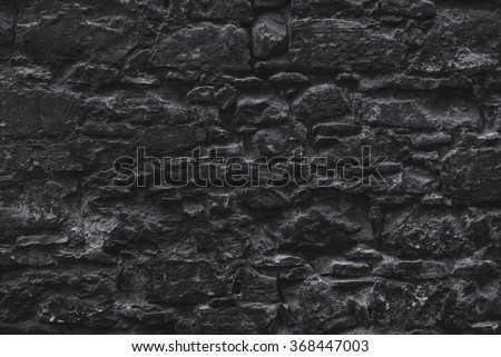 Dark black old medieval natural stone wall. Texture, background or wallpaper