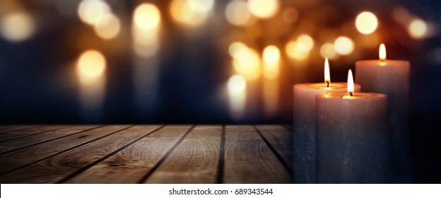 Dark blue background with golden lights and burning candles on a wooden table for a solemn ceremony