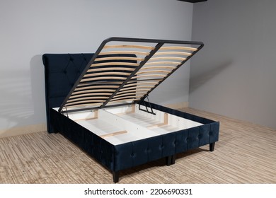 A Dark Blue Bed With A Storage Space Revealed By Lifting The Wooden Slatted Base