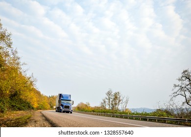 Dark Blue Bonnet Modern American Big Rig Classic Freight Transportation Bonnet Semi Truck With Black Grille Transporting Commercial Cargo In Dry Van Semi Trailer On The Winding Autumn Local Road