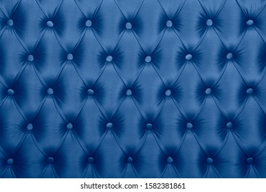 Dark blue capitone textile background, classic retro Chesterfield style checkered soft tufted fabric furniture diamond pattern decoration with buttons, close up