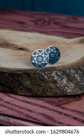 Dark Blue Cuff Link In The Shape Of A Circle With Silver Lines Isolated On A Wooden Background.