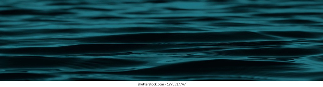 Dark blue green abstract background. Reflection of light on a smooth surface of water with small waves. Tidewater green background with copy space for design. Web banner.