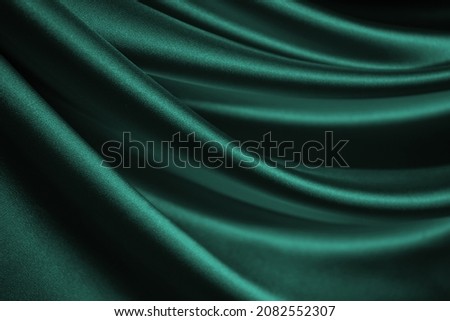  Dark blue green silk satin. Wavy soft folds. Shiny fabric surface. Luxury emerald green background with space for design. Web banner. Birthday, Christmas, Valentine, holiday, festive, paty, award.   